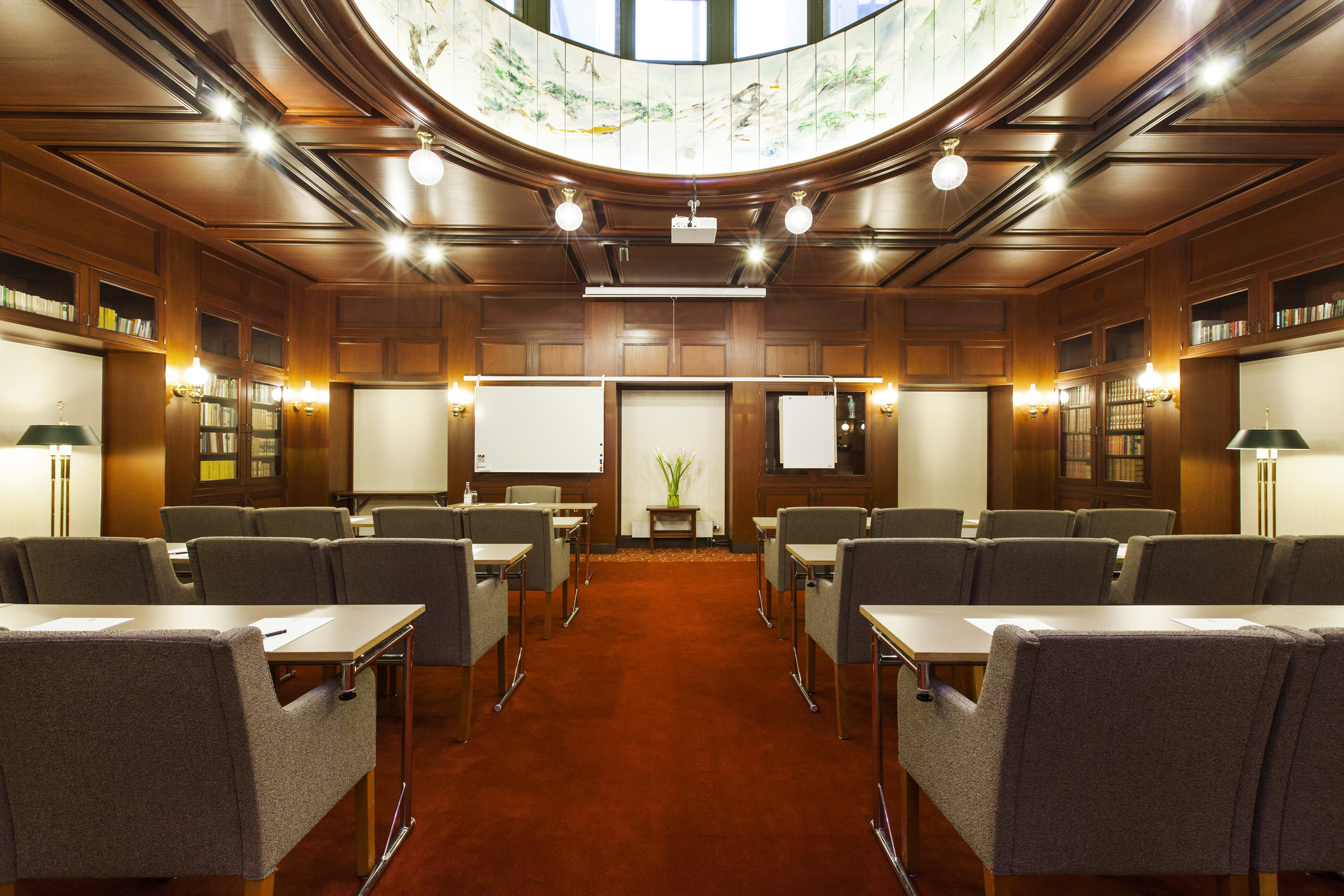 Conference room with elegant wood paneling and comfortable chairs, classic-style decor with a round domed ceiling and bookshelves