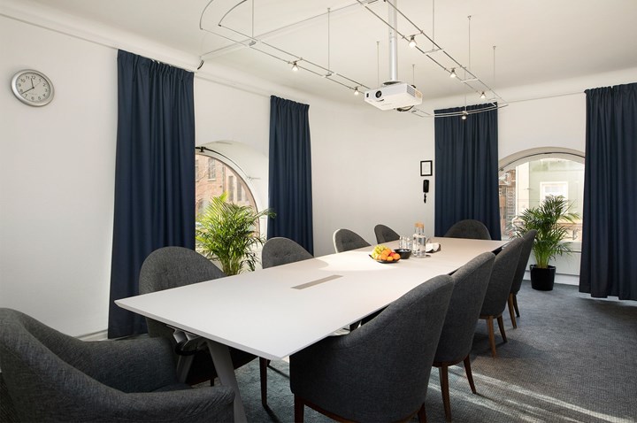 Board room with white walls, large windows and dark curtains