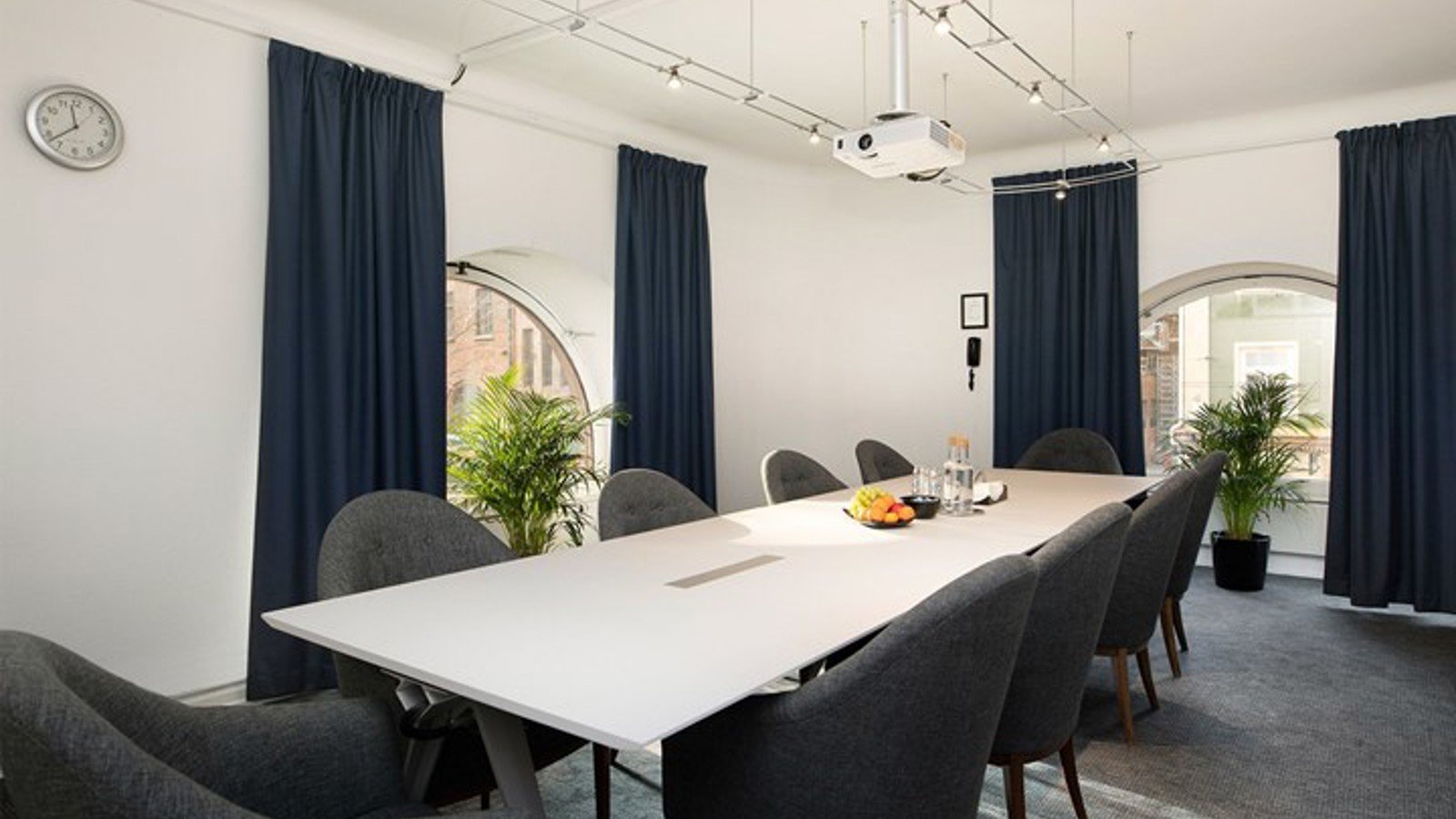 Board room with white walls, large windows and dark curtains
