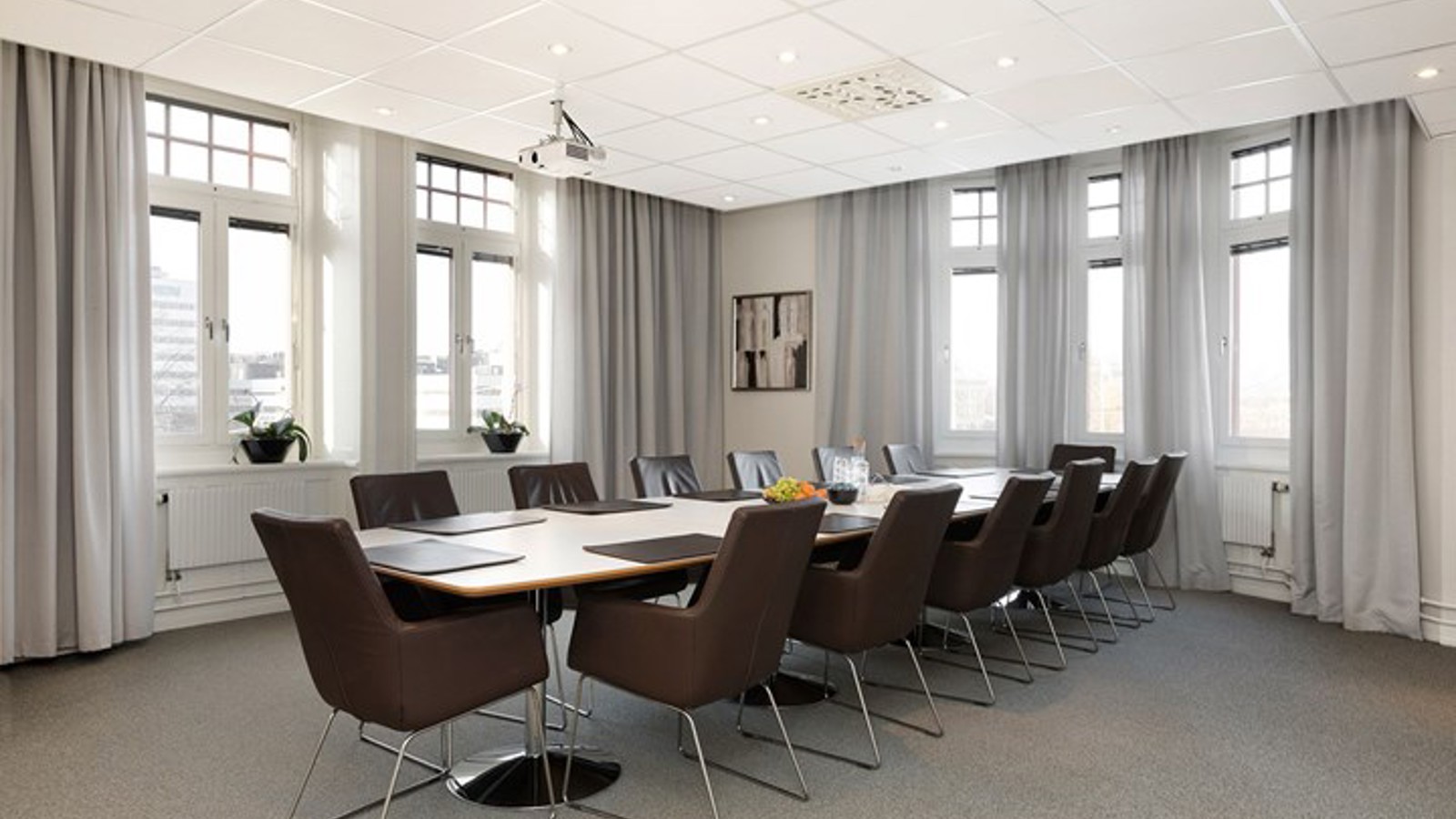 Conference room with board seating, large windows and gray curtains