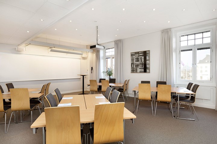 Conference room with island seating, white walls, wooden table and gray floor