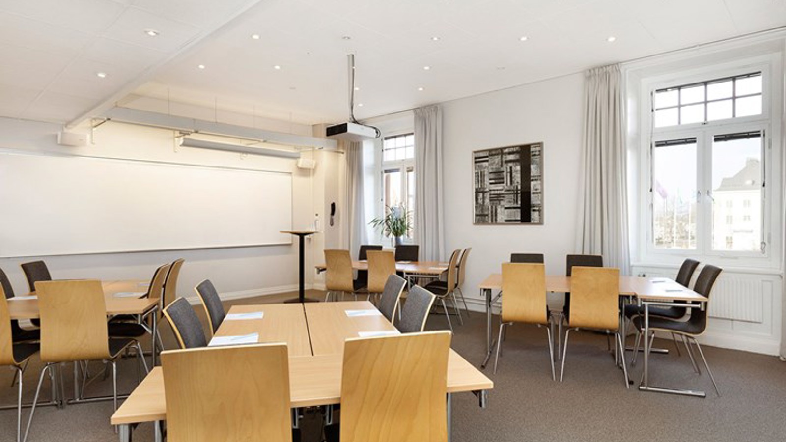 Conference room with island seating, white walls, wooden table and gray floor