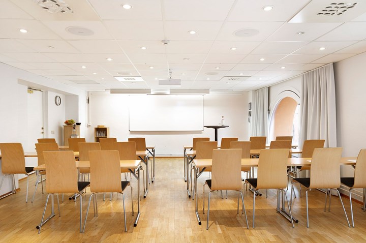 Bright conference room with school seating, white walls and wooden floor