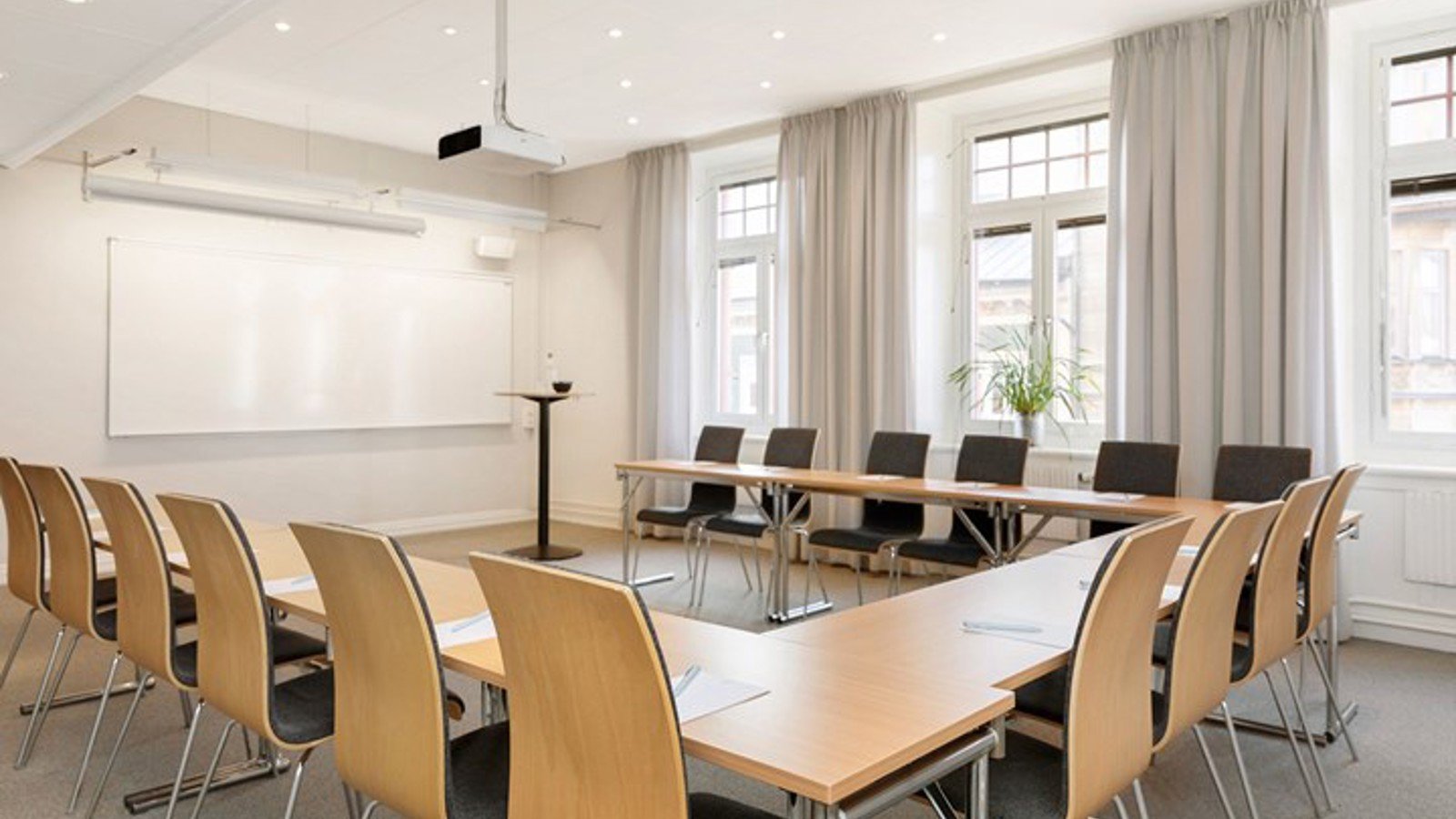 Conference room with u-shaped seating, white walls, large windows and wooden tables