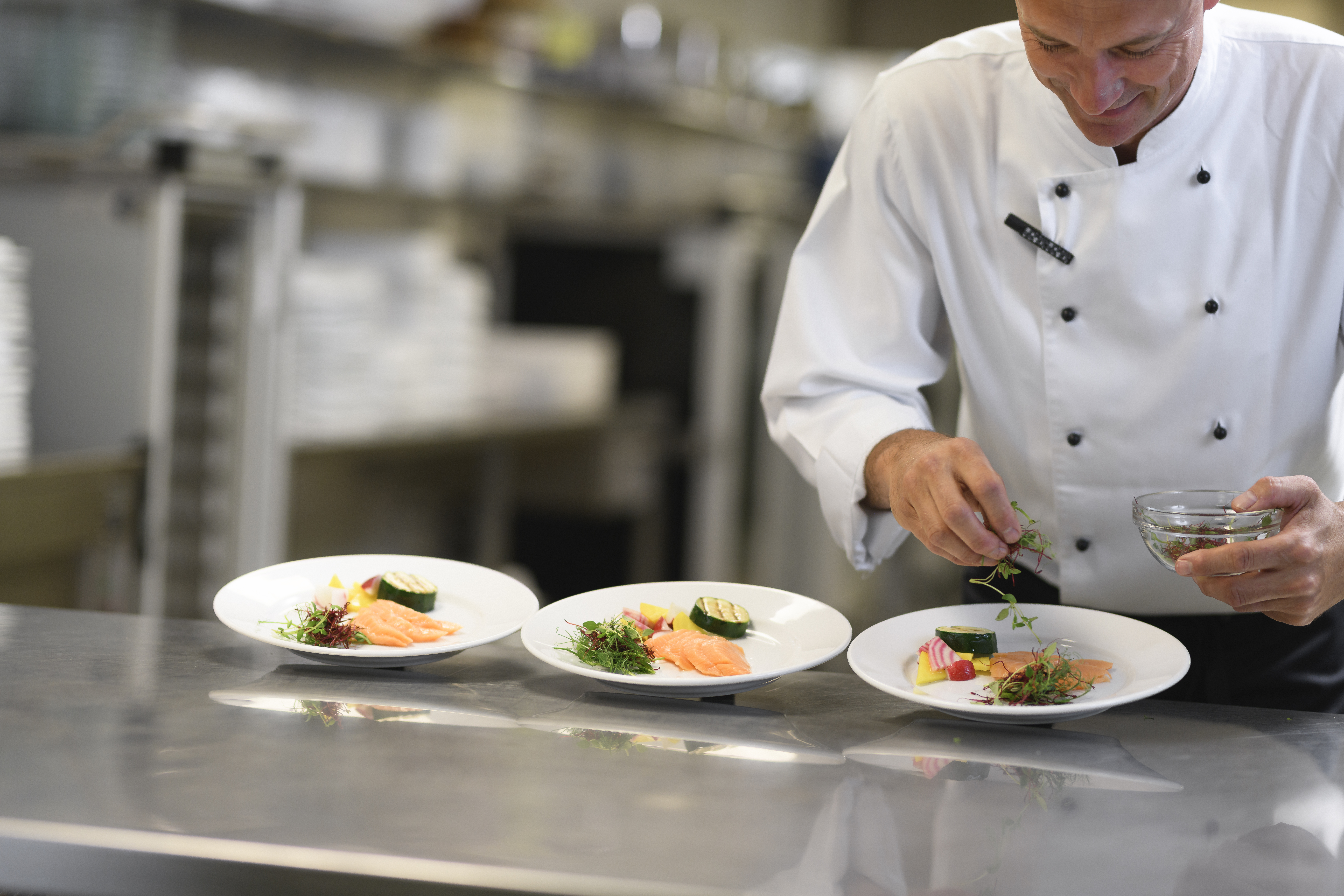Kock som lägger upp mat på tallrikar 