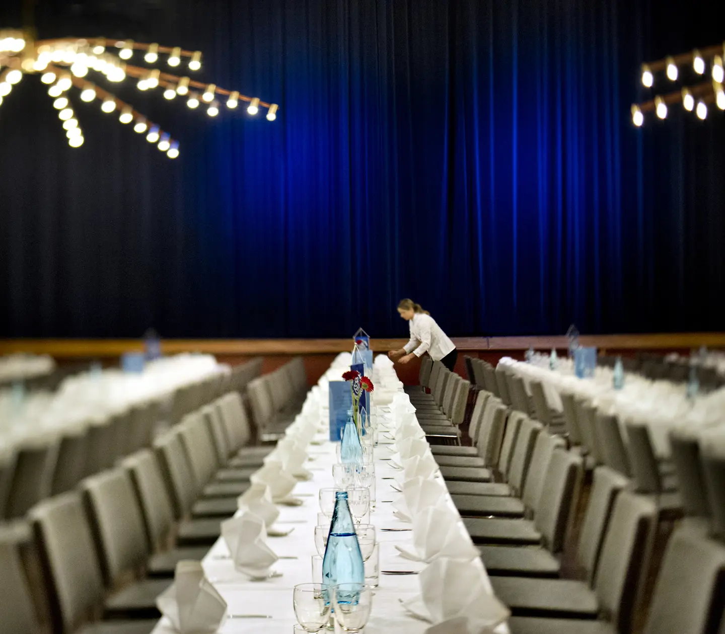 Room set up for banquet, with white tablecloths
