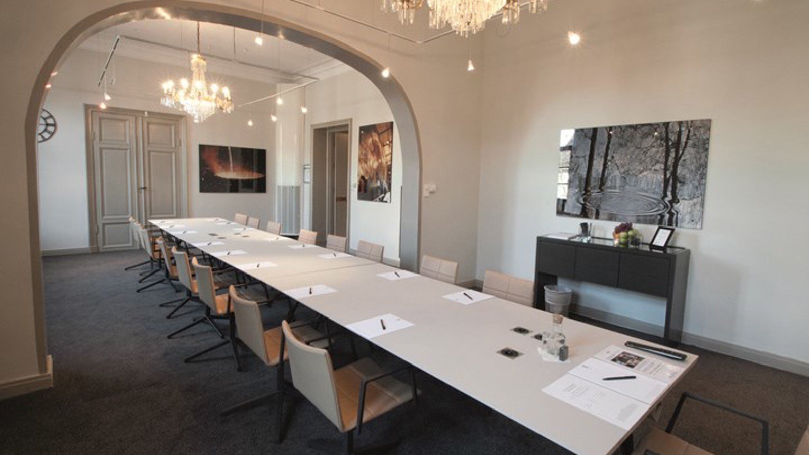 Conference room with board seating, white walls and crystal chandeliers