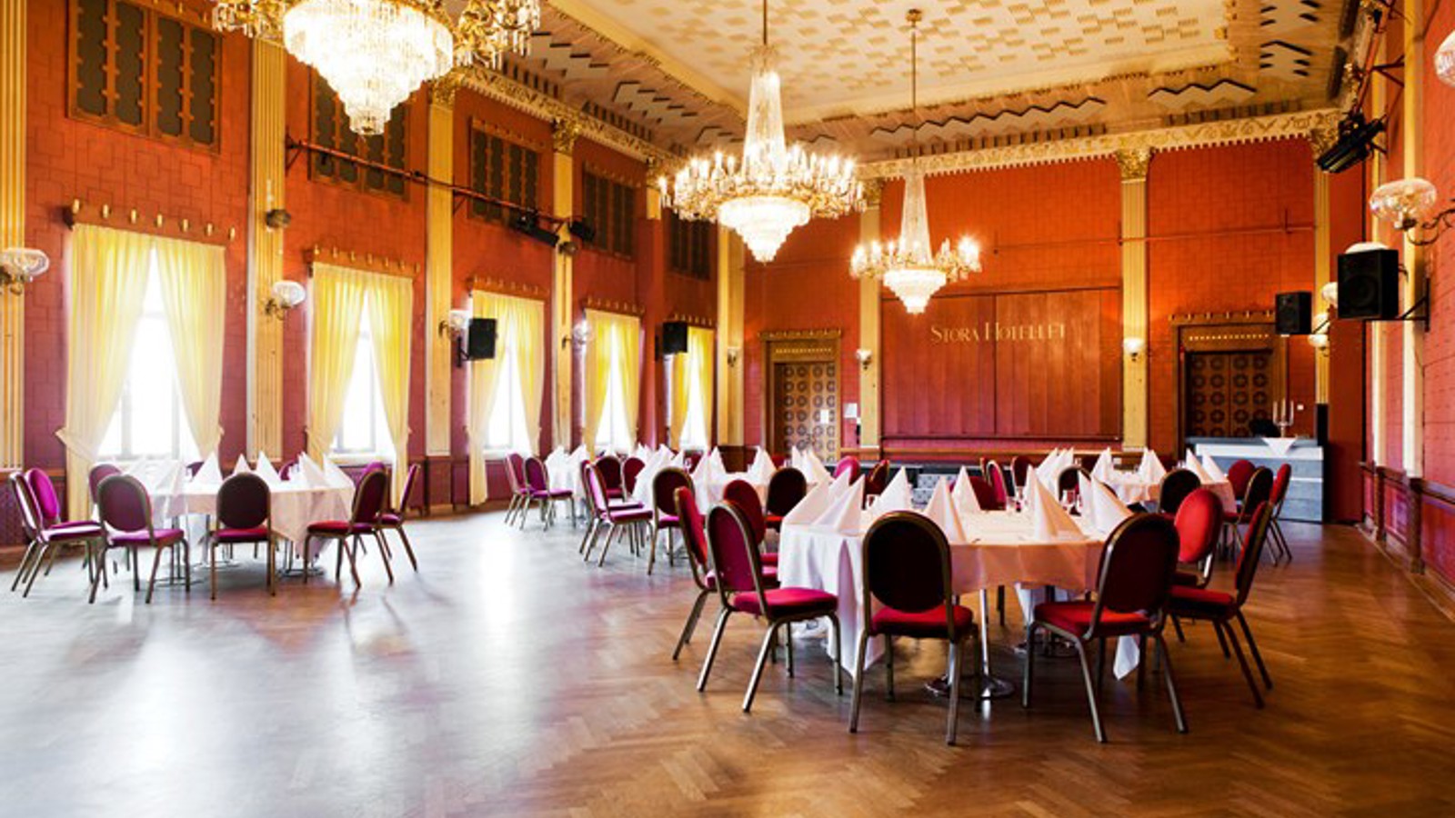 Large party room with red walls, wooden floors and gold details