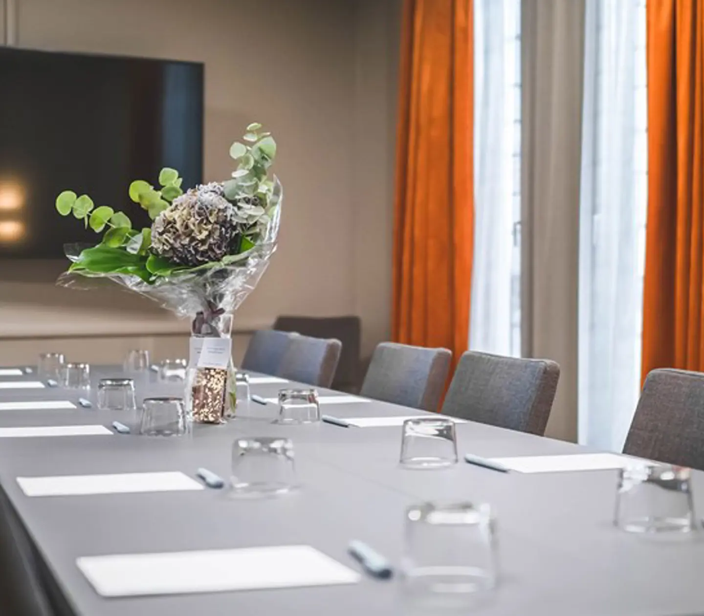 Board room with gray table, gray chairs and rust-brown curtains