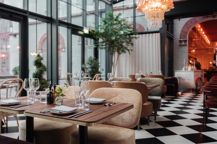 Restaurangmiljö med dukade bord, svart- och vitrutigt golv, stora fönster