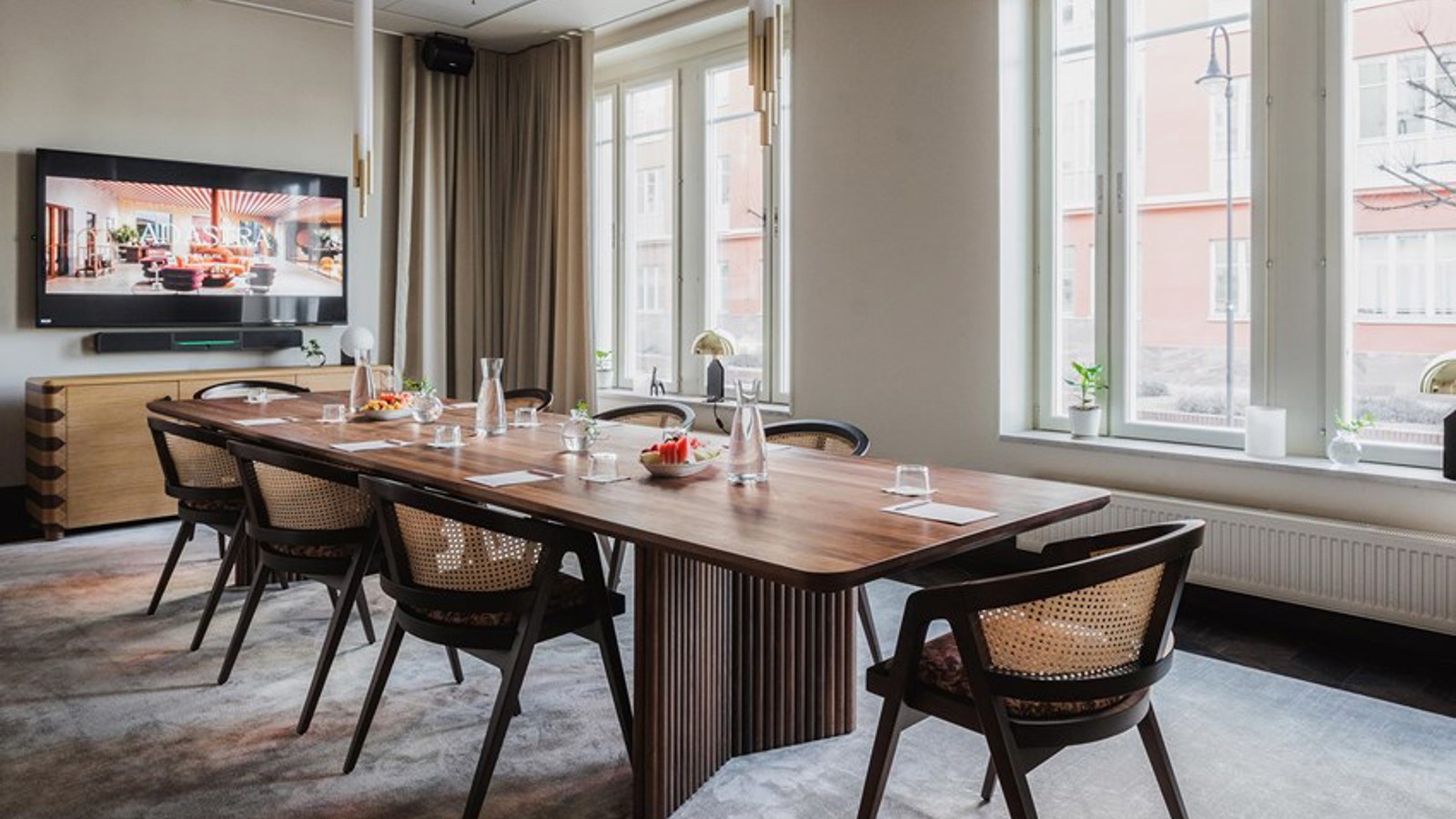 Board room with brown table, large windows and TV screen