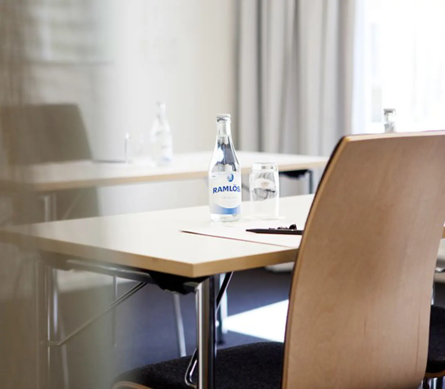 Närbild på konferensmiljö, bord med block, penna och vattenflaska