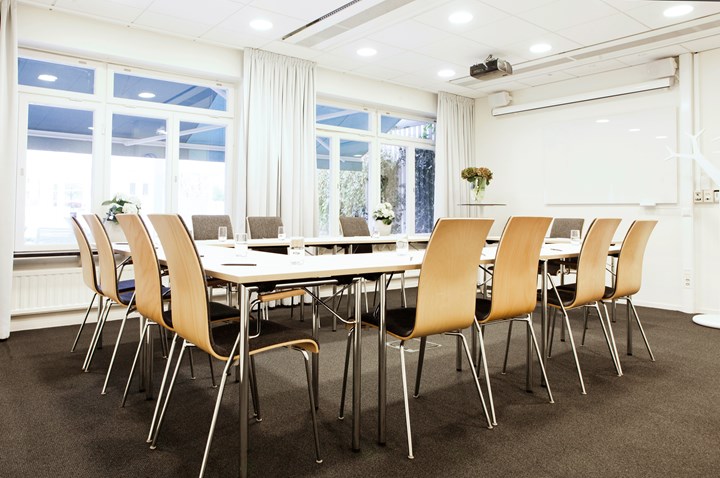Conference room with u-shaped seating, white walls, large windows and gray carpet