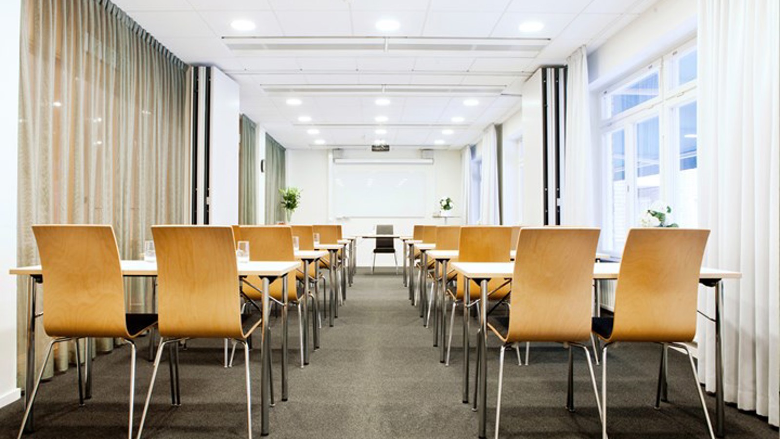 Conference room with school seating, wooden chairs, white walls and large windows