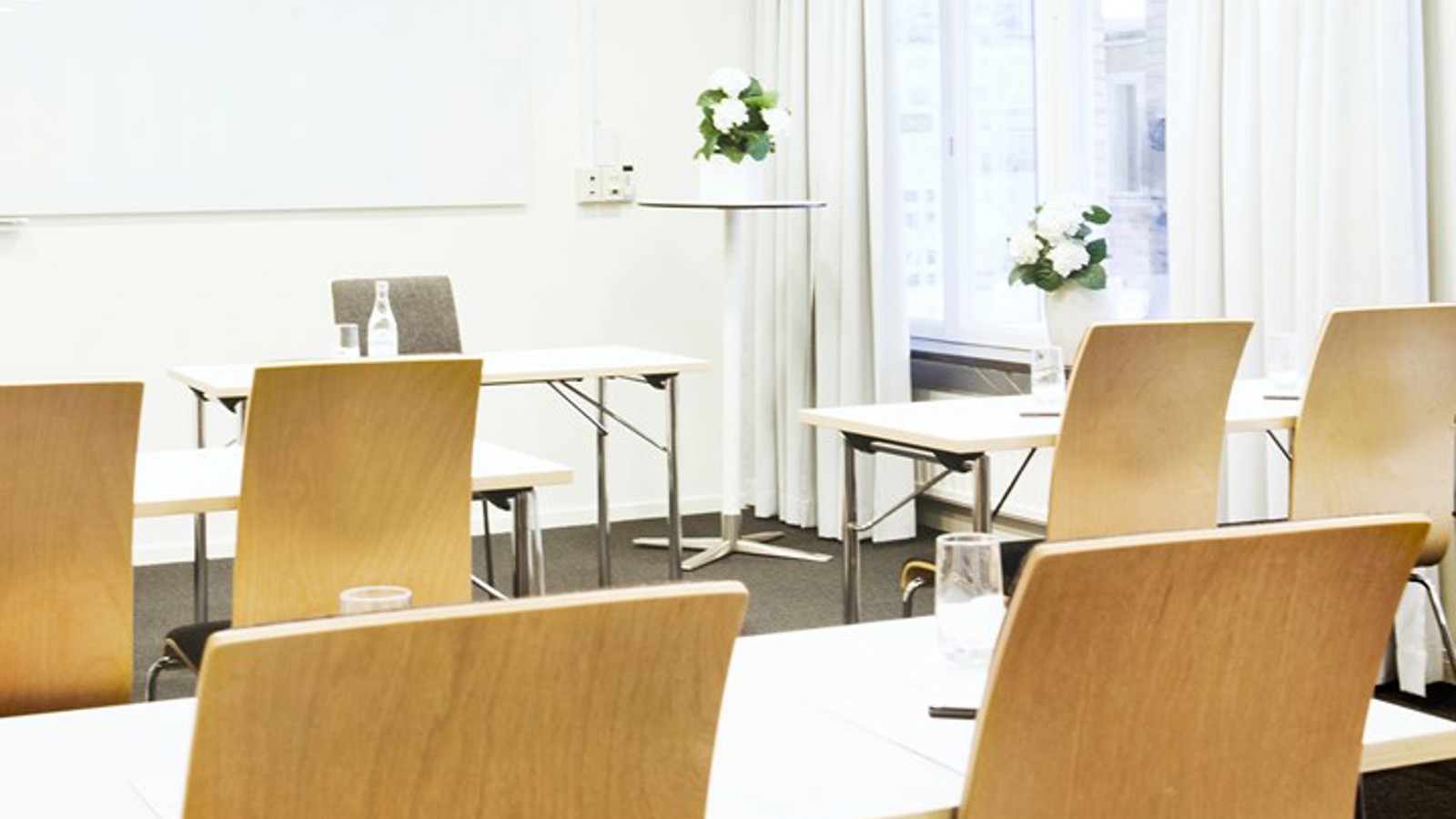 Conference room with school seating, wooden chairs and white walls