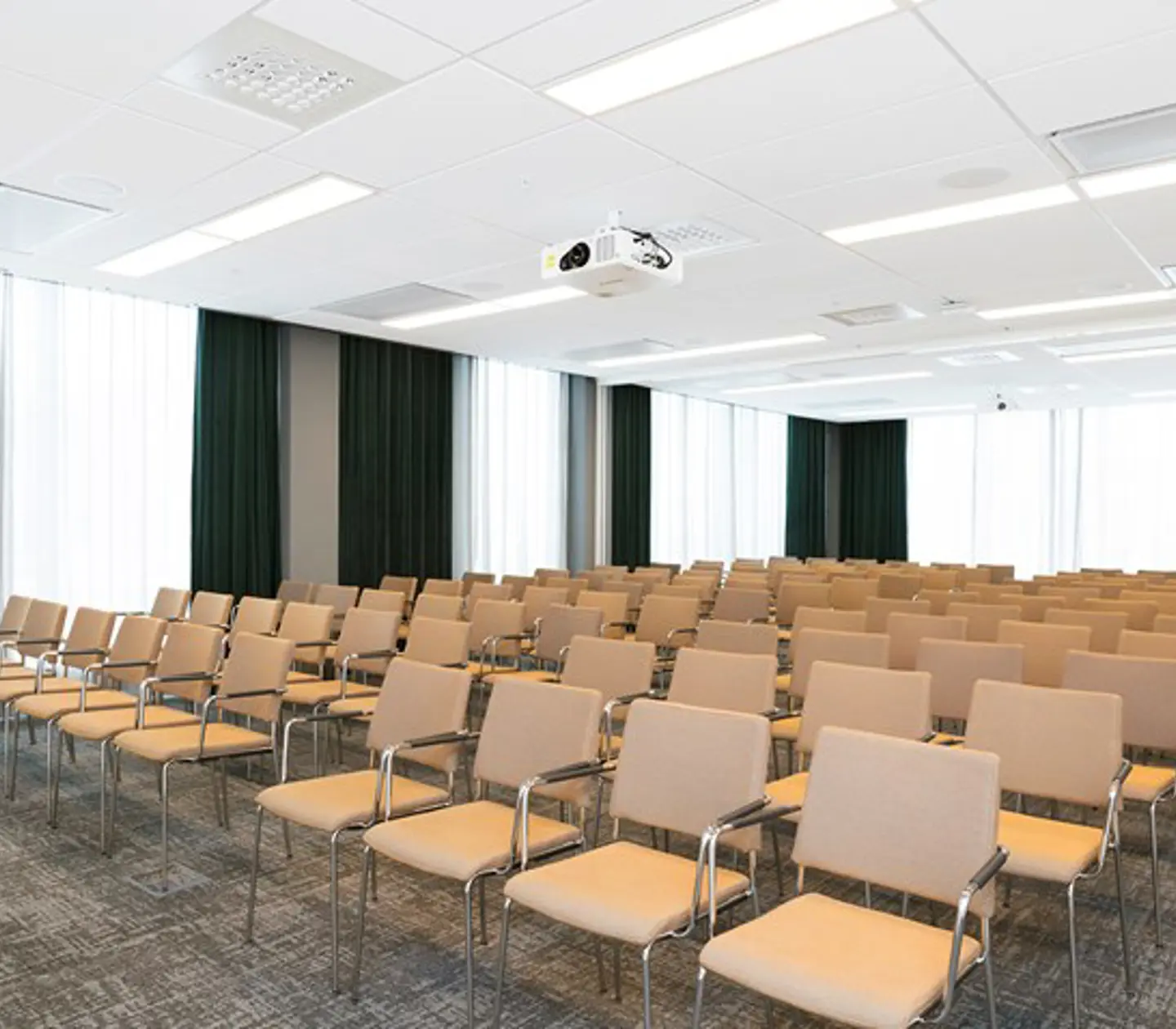 Konferensrum med biosittning, ljusbruna stolar, grått golv vita draperier