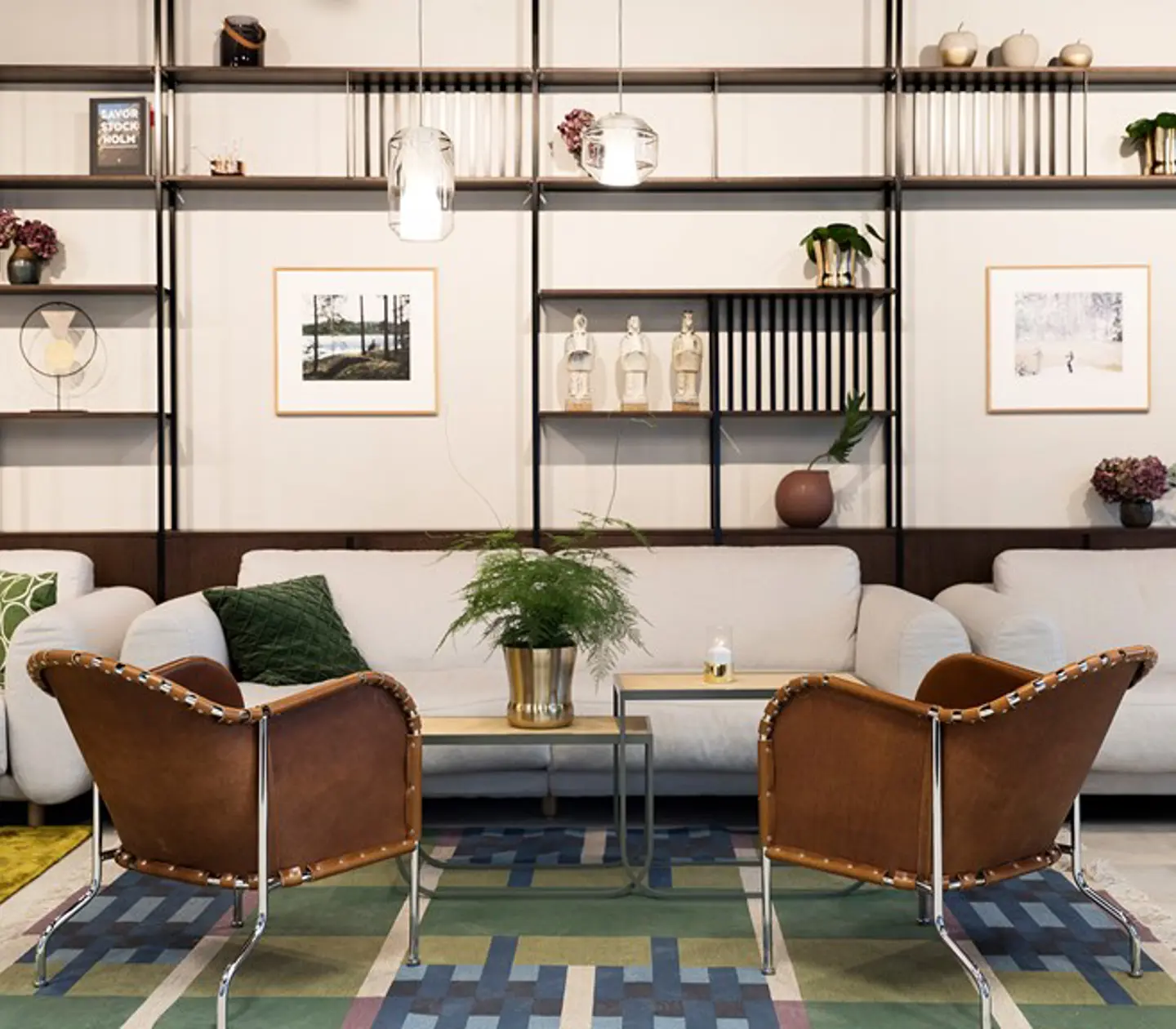 Modern lounge area featuring stylish leather chairs, plush sofas, and a contemporary shelving unit with decorative items and artwork.