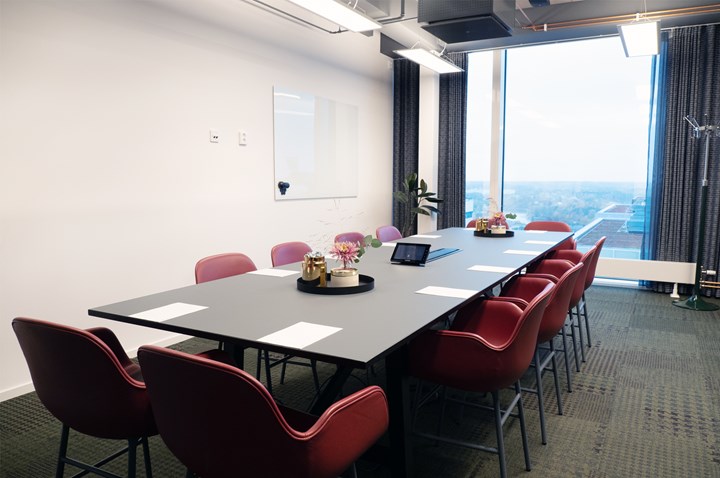 Conference room with board seating, red chairs, black table and large window