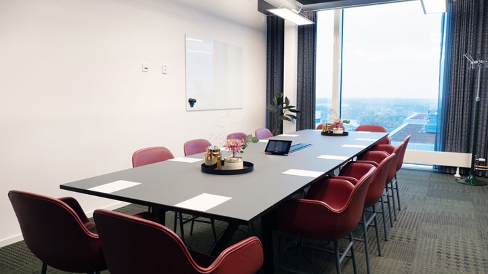 Conference room with board seating, red chairs, black table and large window