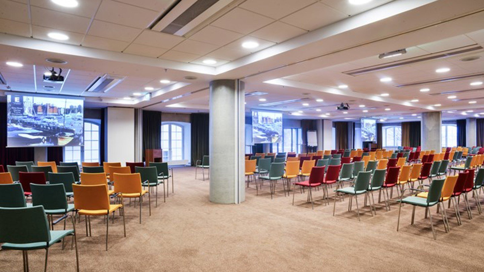 Conference room with cinema seating, colorful chairs and many windows