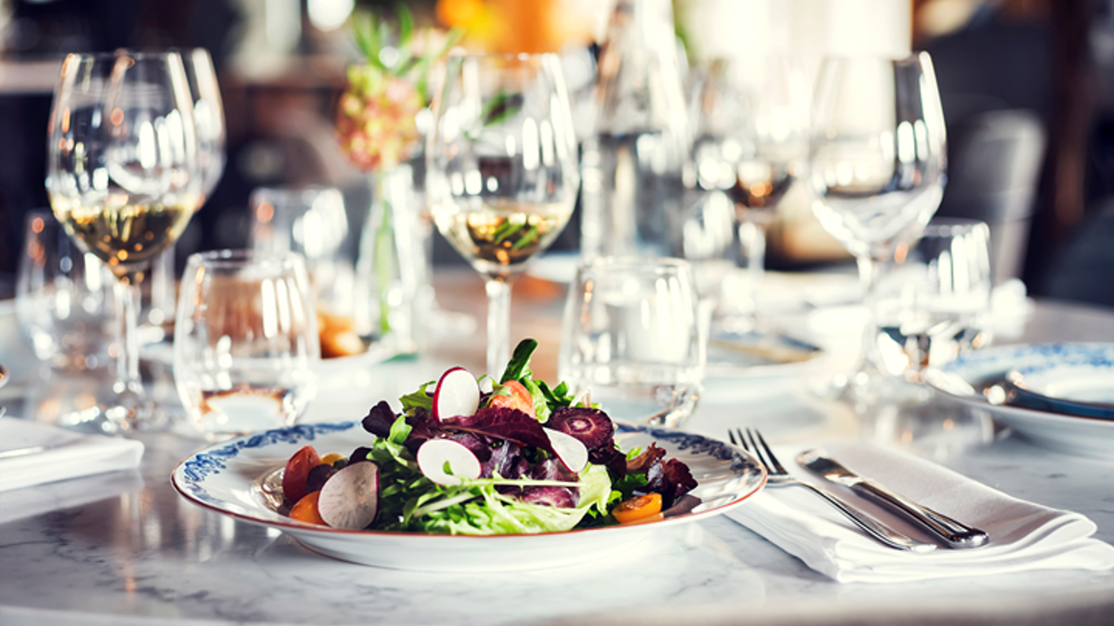 Dukat bord i restaurangmiljö, med sallad i närbild
