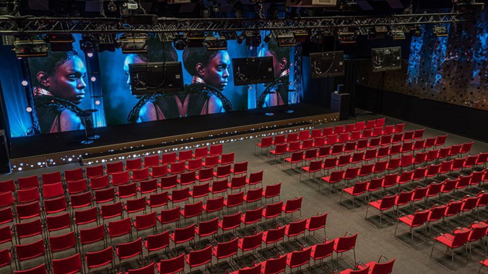 Large venue with cinema seating, red chairs and a projector