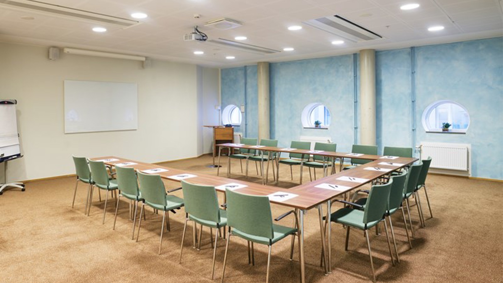 Conference room with U-shaped seating, light blue background wall and round windows