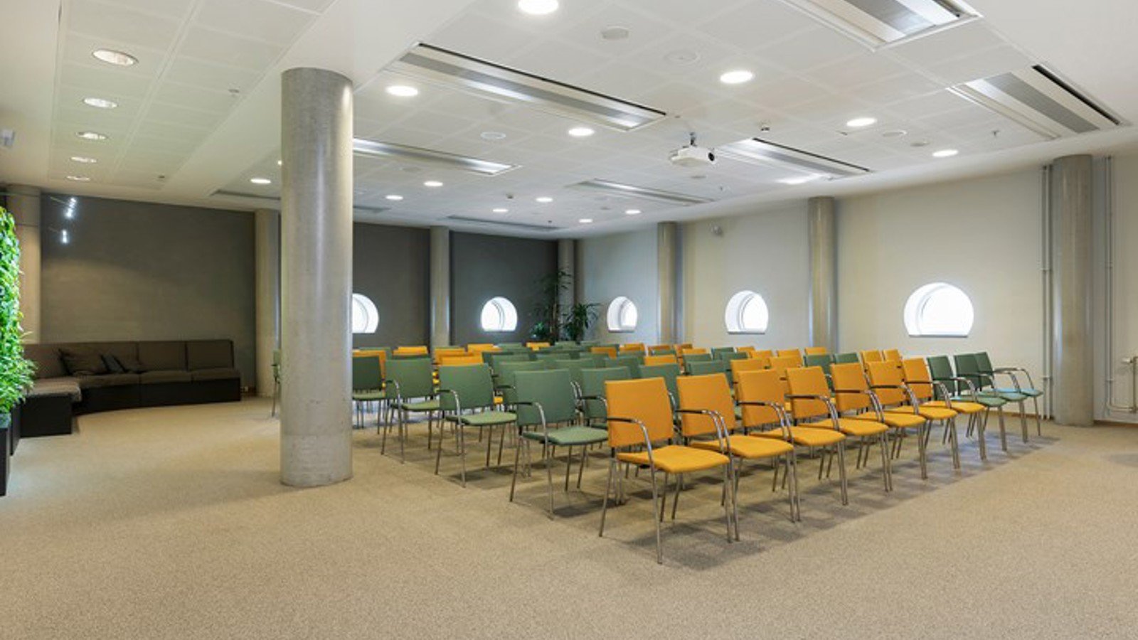 Conference room with cinema seating, yellow and blue chairs and round windows