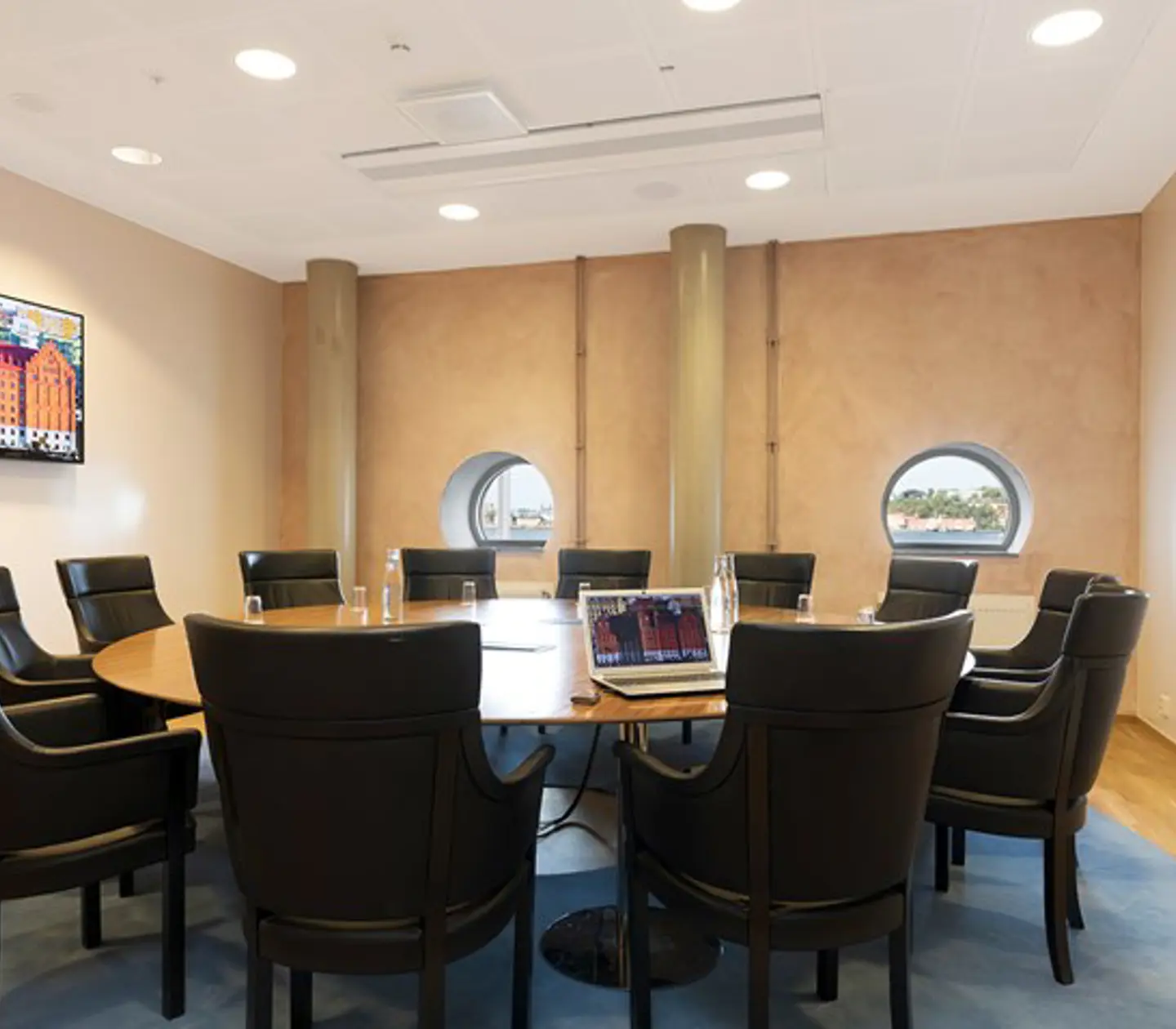 Konferensrum med runt bord, svarta fåtöljer och små runda halvmånefönster