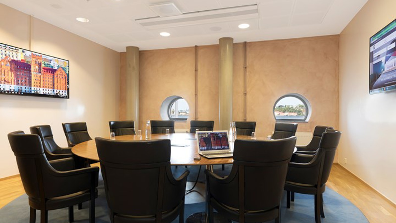 Conference room with round table, black armchairs and small round windows