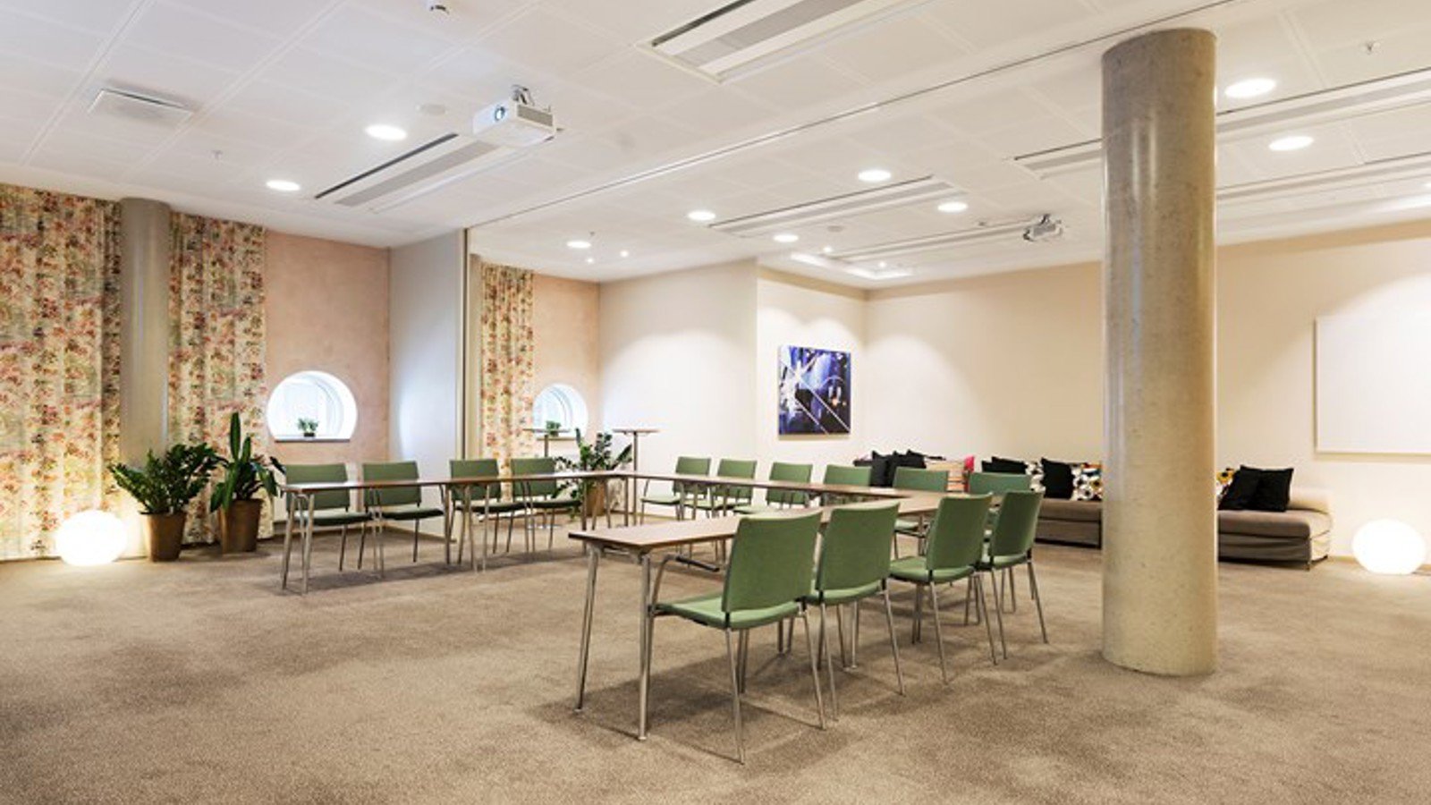 Conference room with u-shaped seating, light brown floor, green chairs and patterned draperies