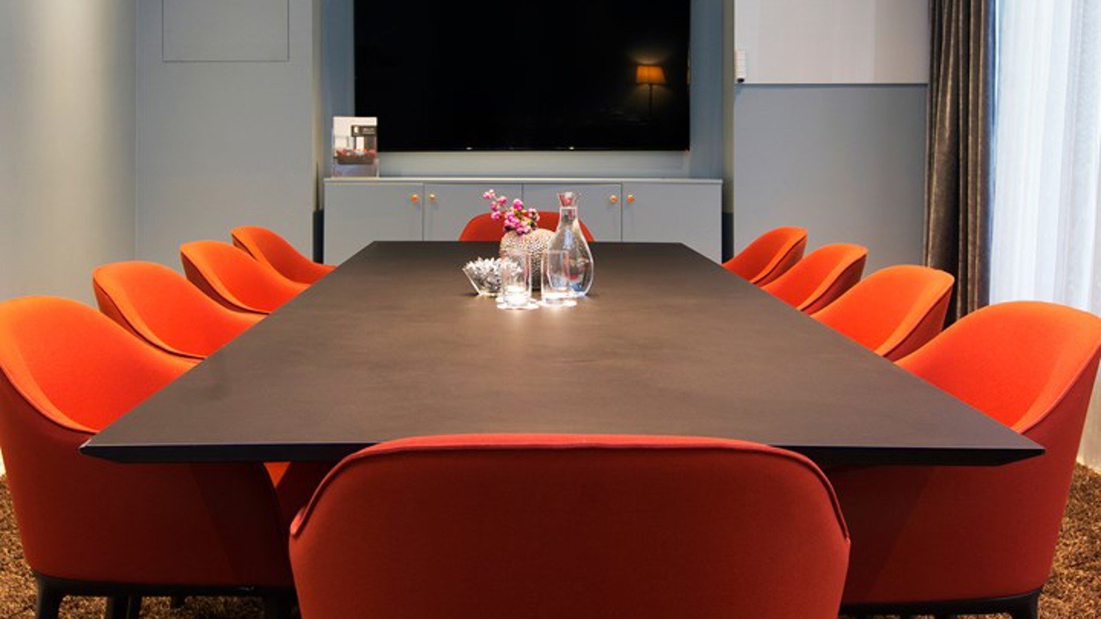 Conference room with board seating, brown table, red chairs and blue walls