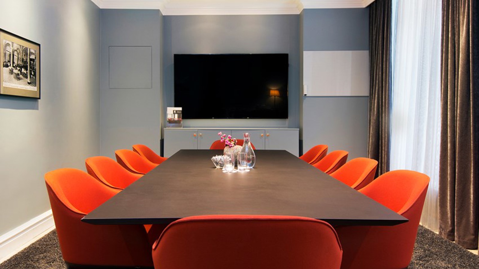 Board room with dark brown table, red chairs and blue walls