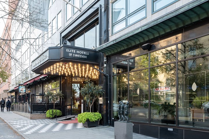 Hotellentré med lampor, trottoar, skyltfönster