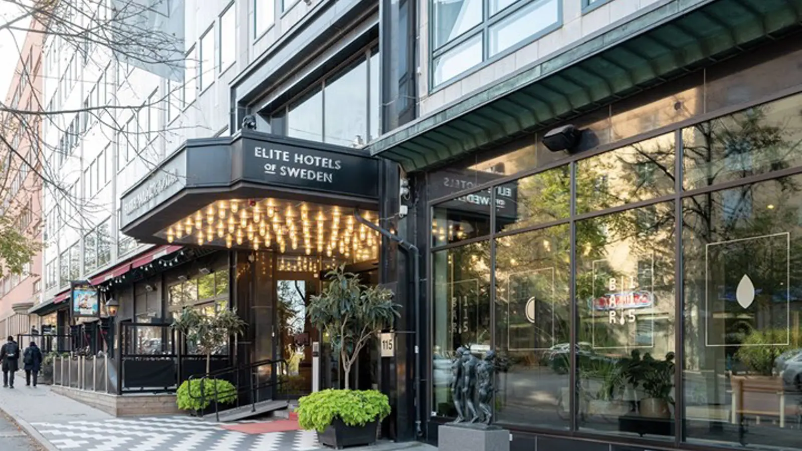 Hotel entrance with lights, sidewalk and big windows