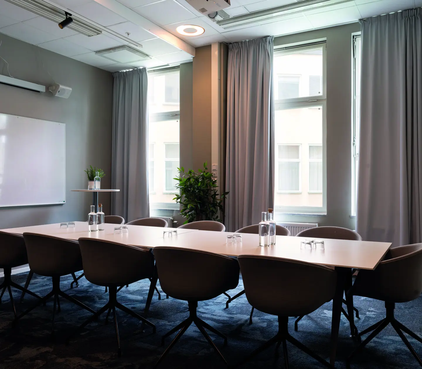 Conference room with school seating, large windows, wooden table, blue carpet