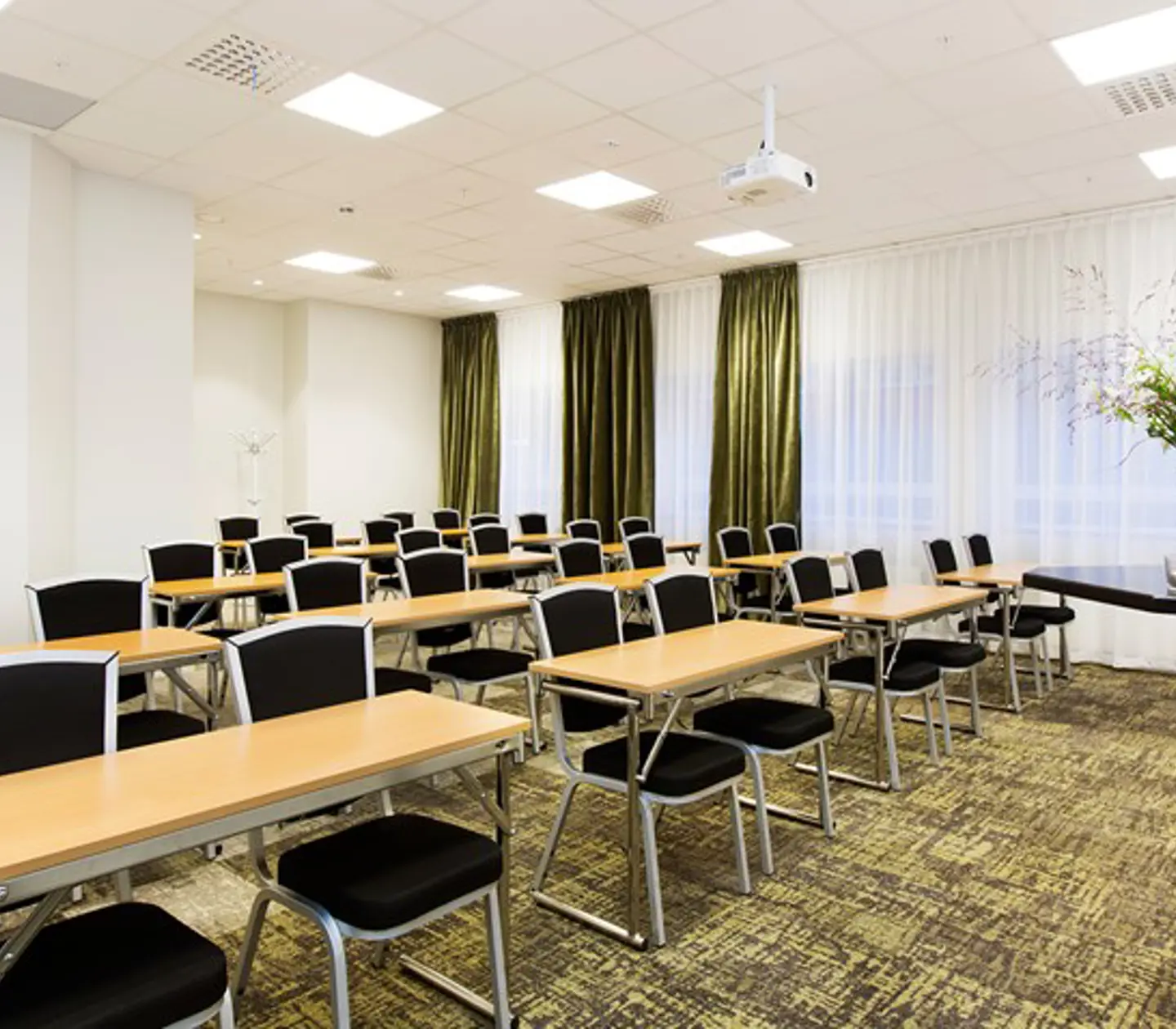 Conference room with school seating, white walls, black chairs, wooden table