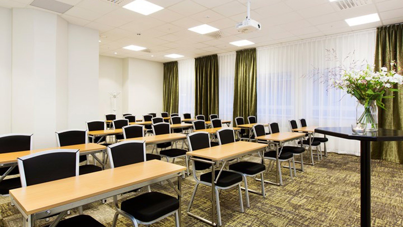 Conference room with school seating, white walls, black chairs, wooden table