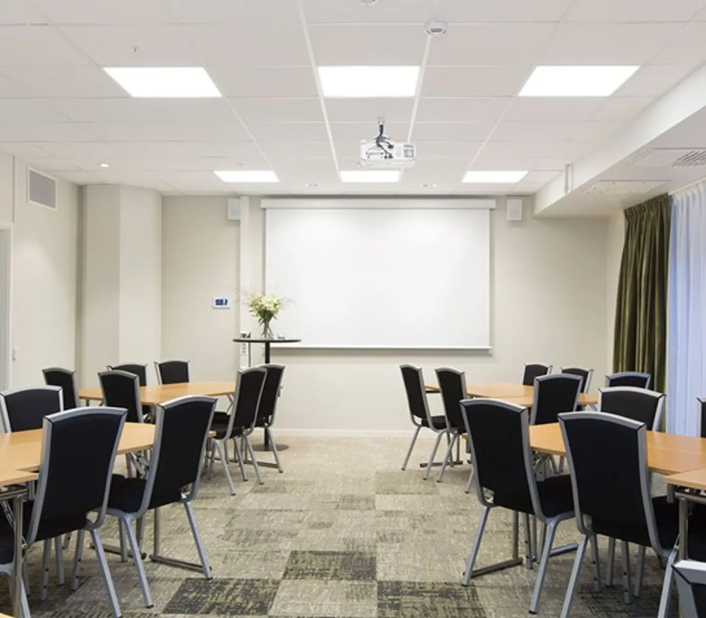 Conference room with island seating, white walls, black chairs, wooden table