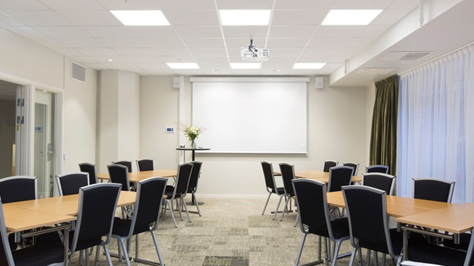 Conference room with island seating, white walls, black chairs, wooden table