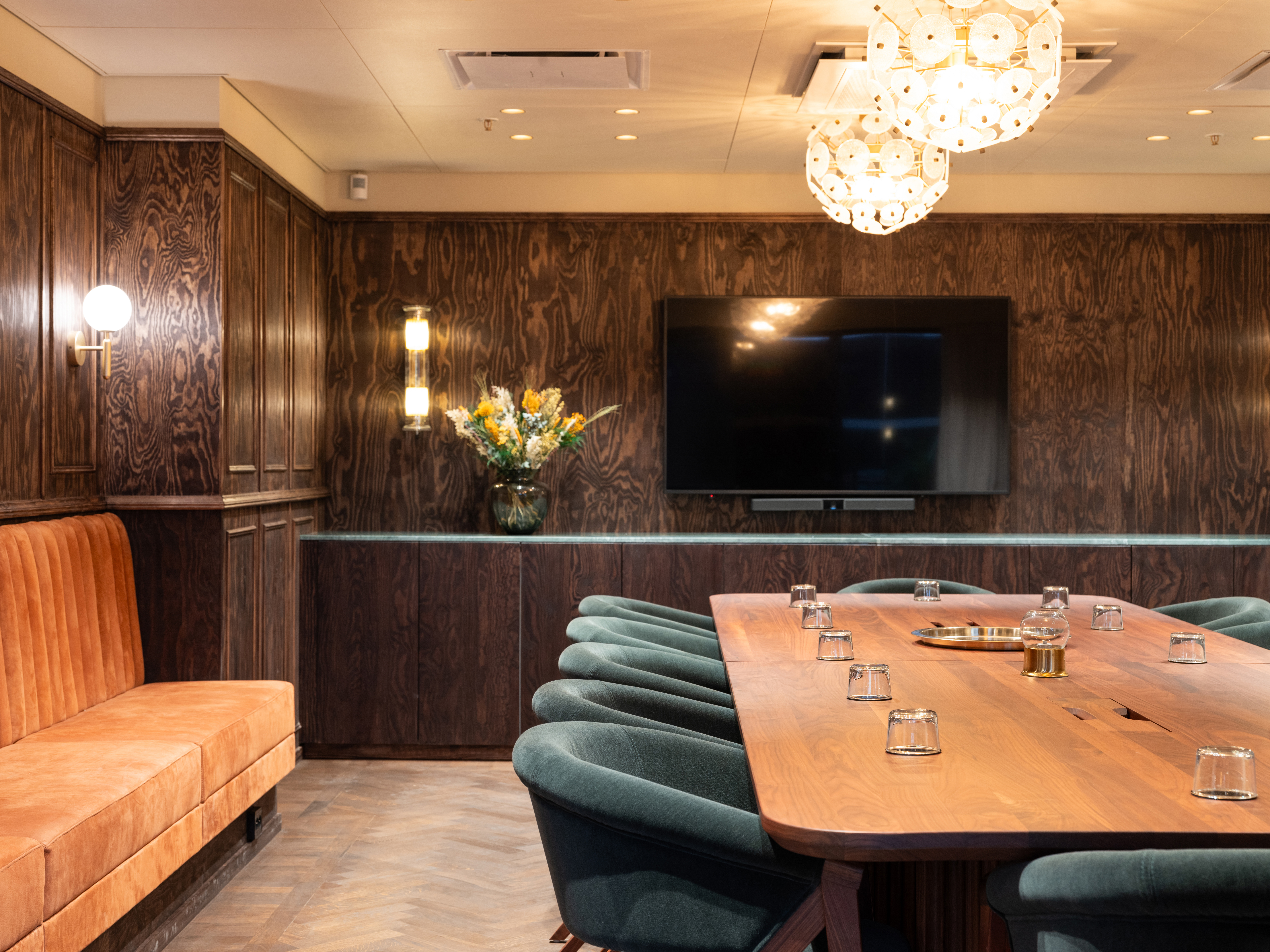 Konferensrum med mörka väggar, orange soffa och blåa stolar