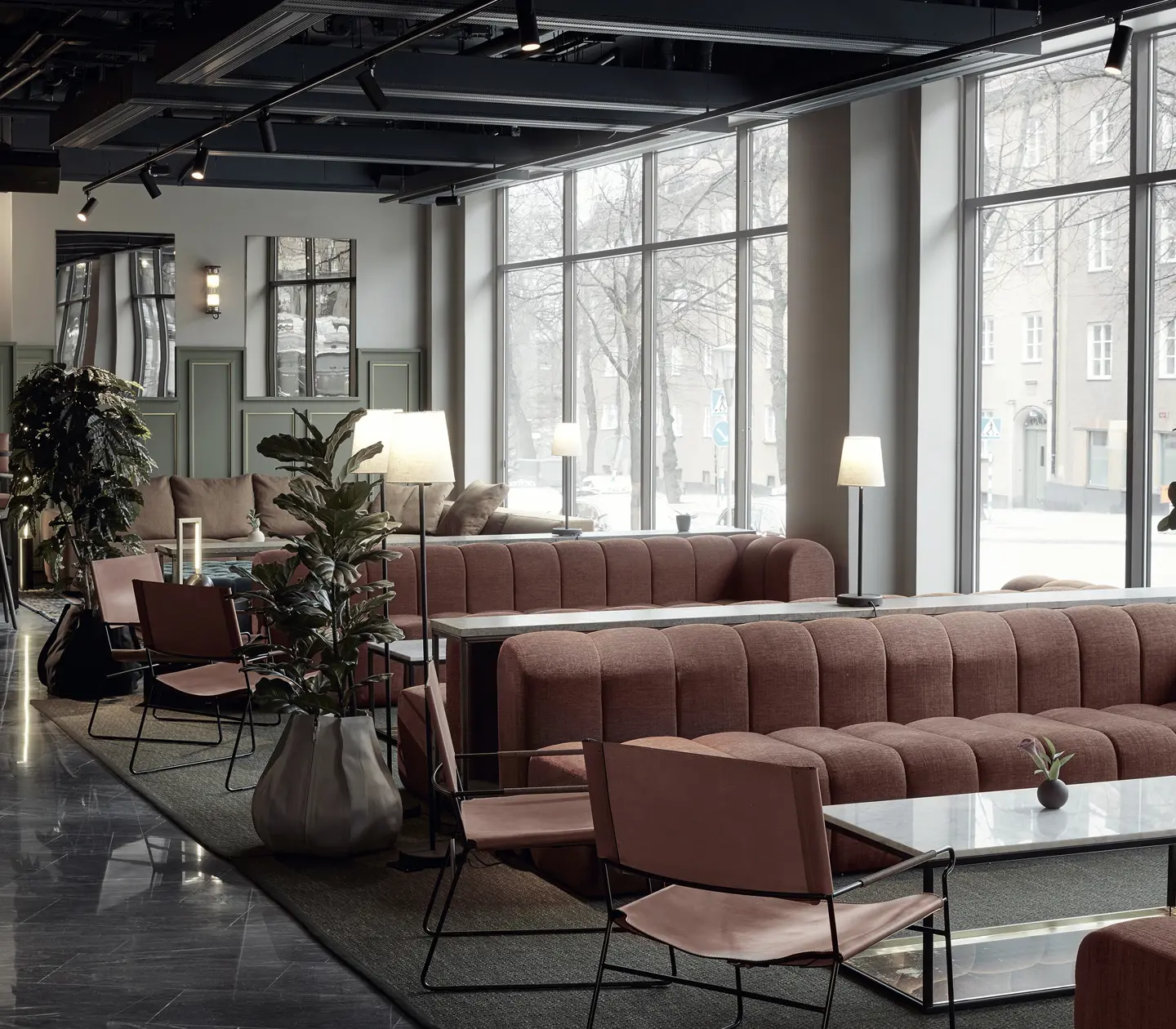 Modern lounge interior with pink sofas, large windows, and green plants, featuring contemporary lighting and marble flooring.