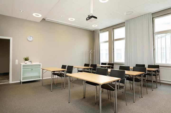 Konferensrum med skolsittning, stora fönster, brun matta, träbord