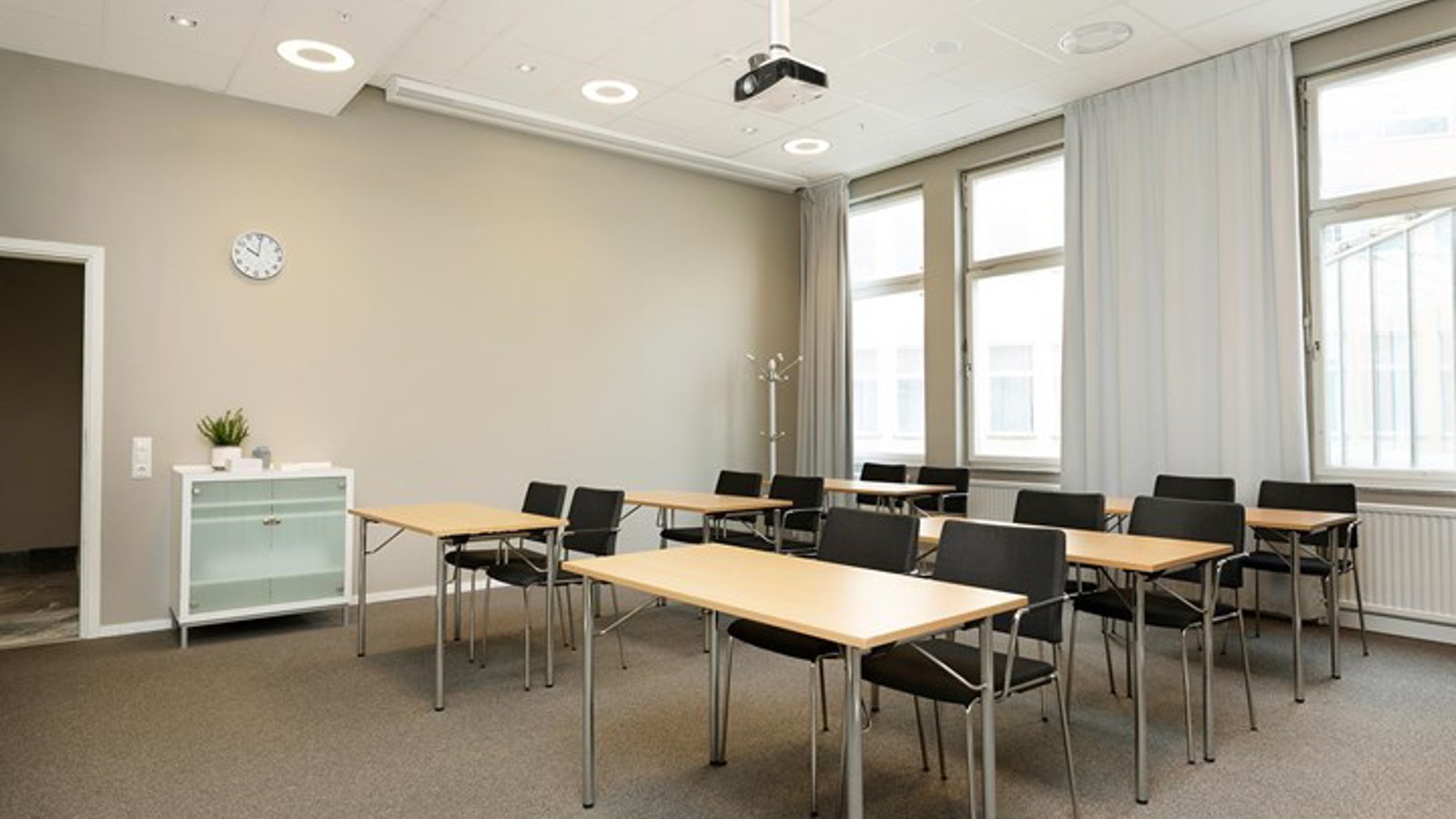 Conference room with school seating, large windows, brown carpet, wooden table