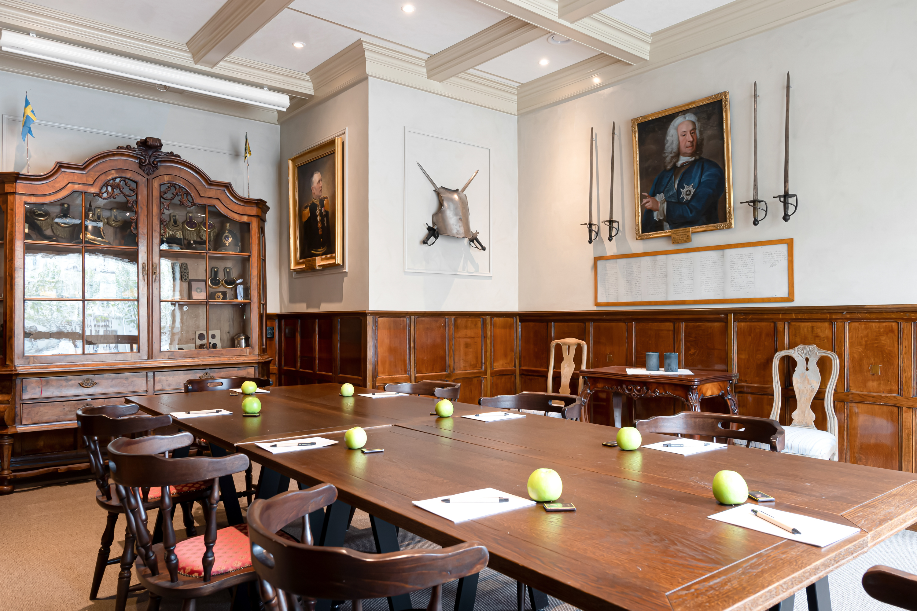 Rum inrett i engelsk stil med mörk träpanel, ett stort bord och tavlor på väggarna.