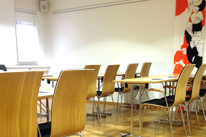 Ljust konferensrum i skolsittning med trägolv och vita väggar
