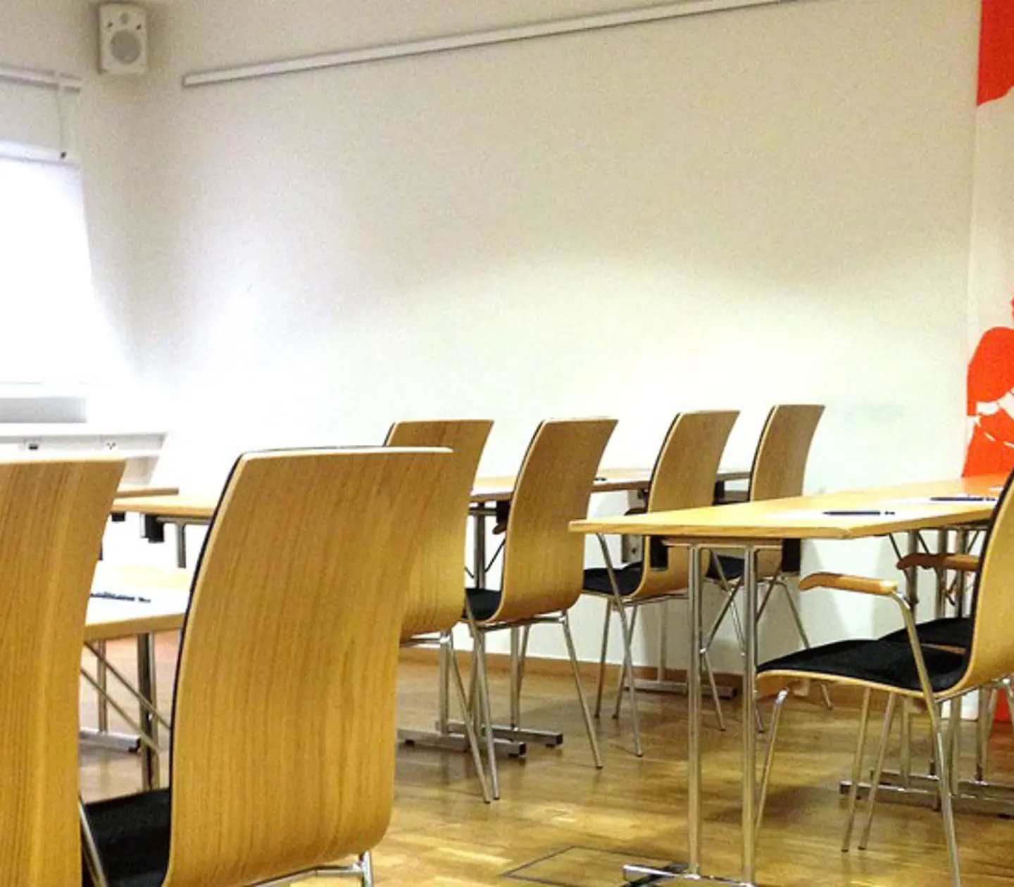 Bright conference room in a school setting with wooden floors and white walls