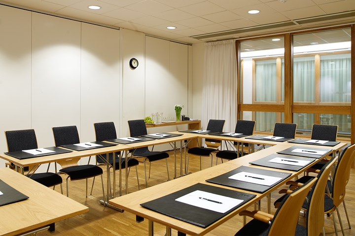 Ljust konferensrum med vita väggar och u-sittning