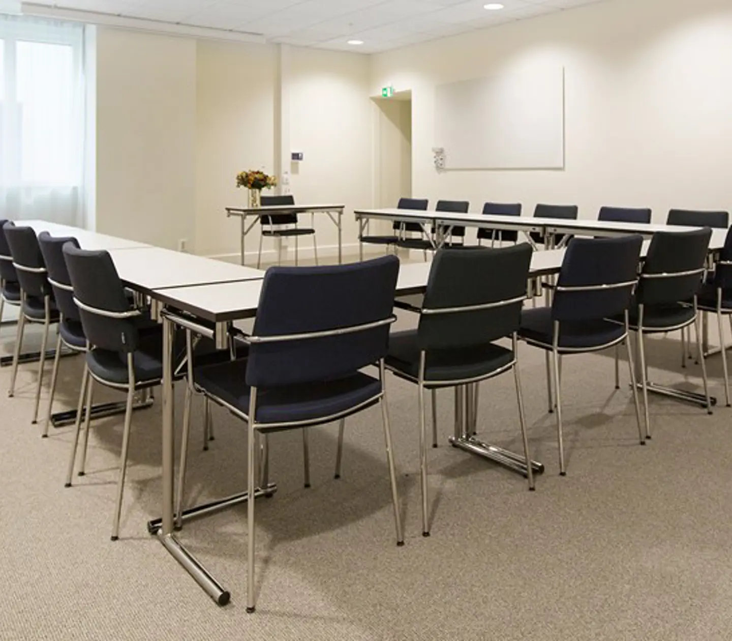 Bright conference room with u-shaped seating, white walls and black chairs