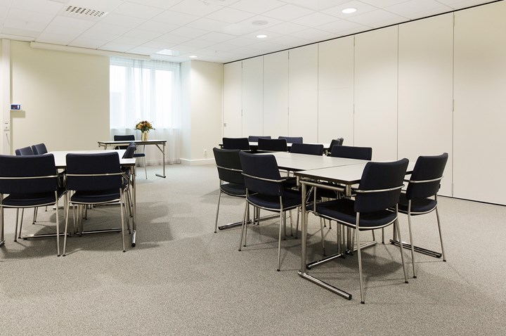 Conference room with island seating, light ceiling, light walls and black chairs